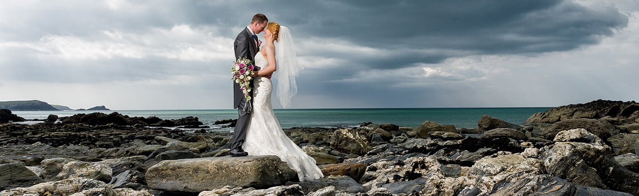 Couple kissing on Fistral Beach on their wedding day